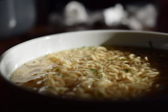 Close-up of a steaming bowl of Lanzhou beef noodle soup with hand-pulled noodles.