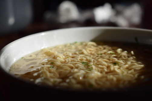 High-definition close-up of steaming instant noodles in a clean white bowl, highlighting texture and freshness.