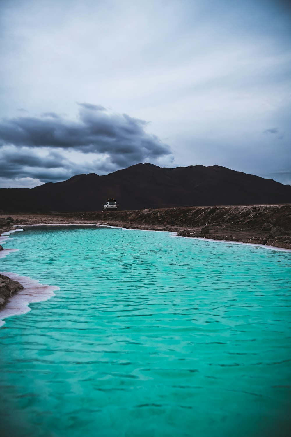 body of water beside brown mountain