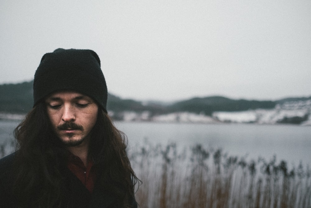 man wearing knit cap near body of water