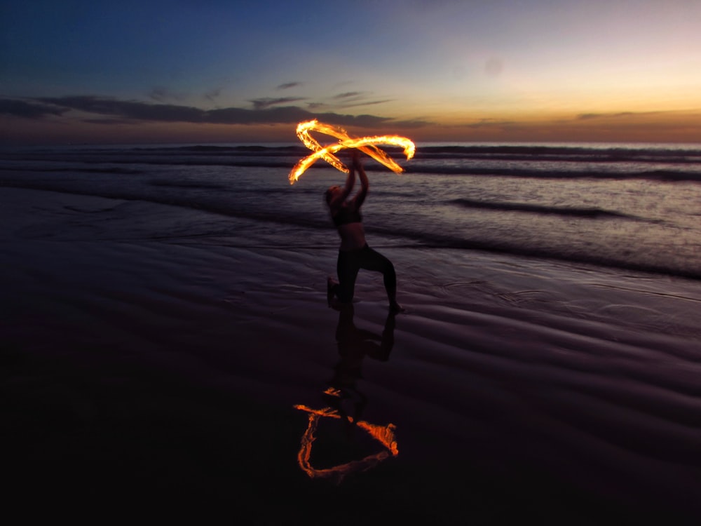 personne faisant de la danse du feu au bord de la mer