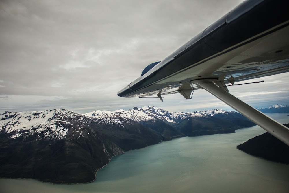 aerial view photography of airplane wing above snow mountain