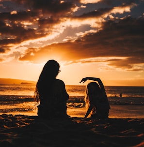 silhouette photo of woman and girl on shoreline