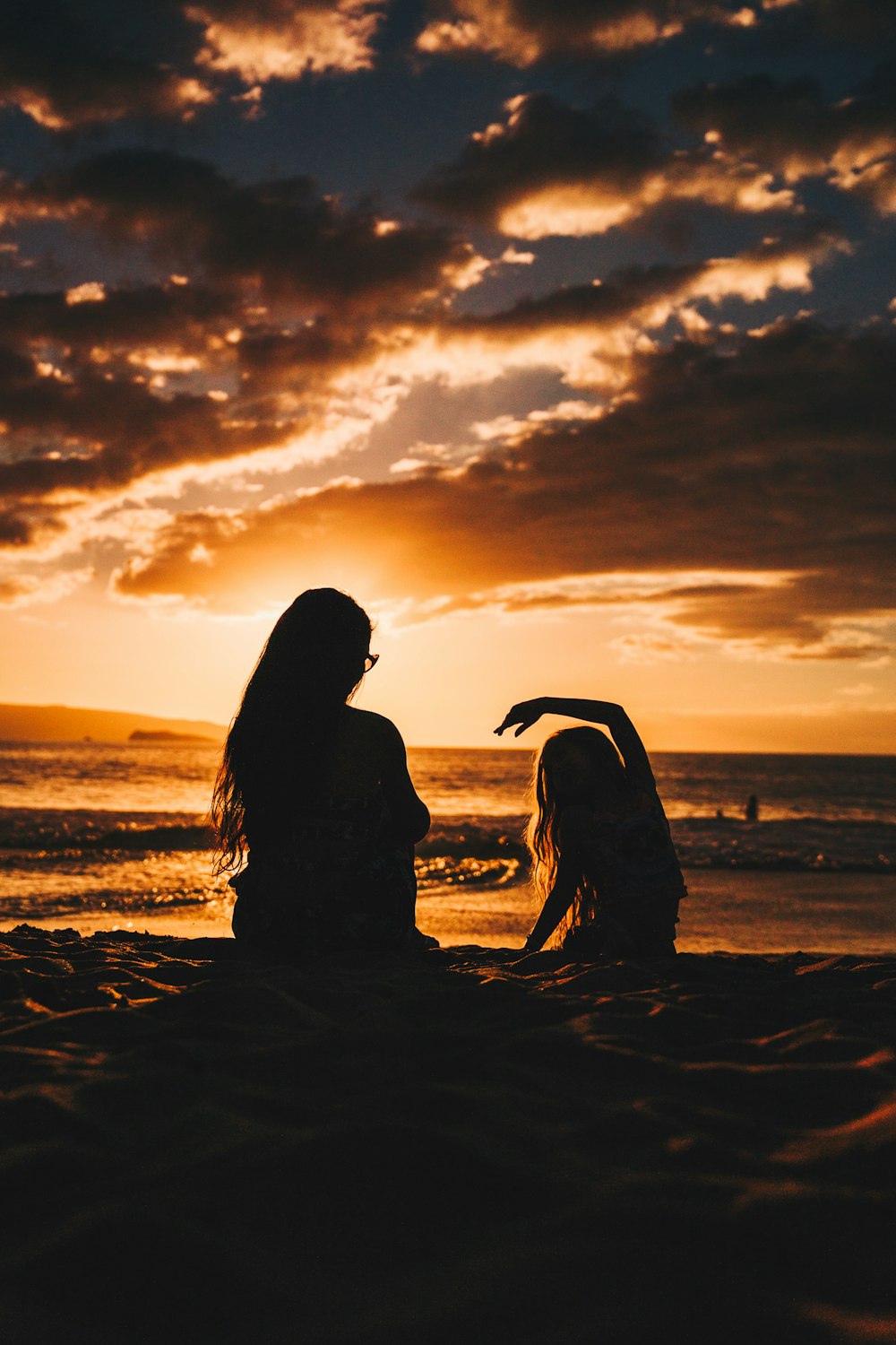 silhouette photo of woman and girl on shoreline