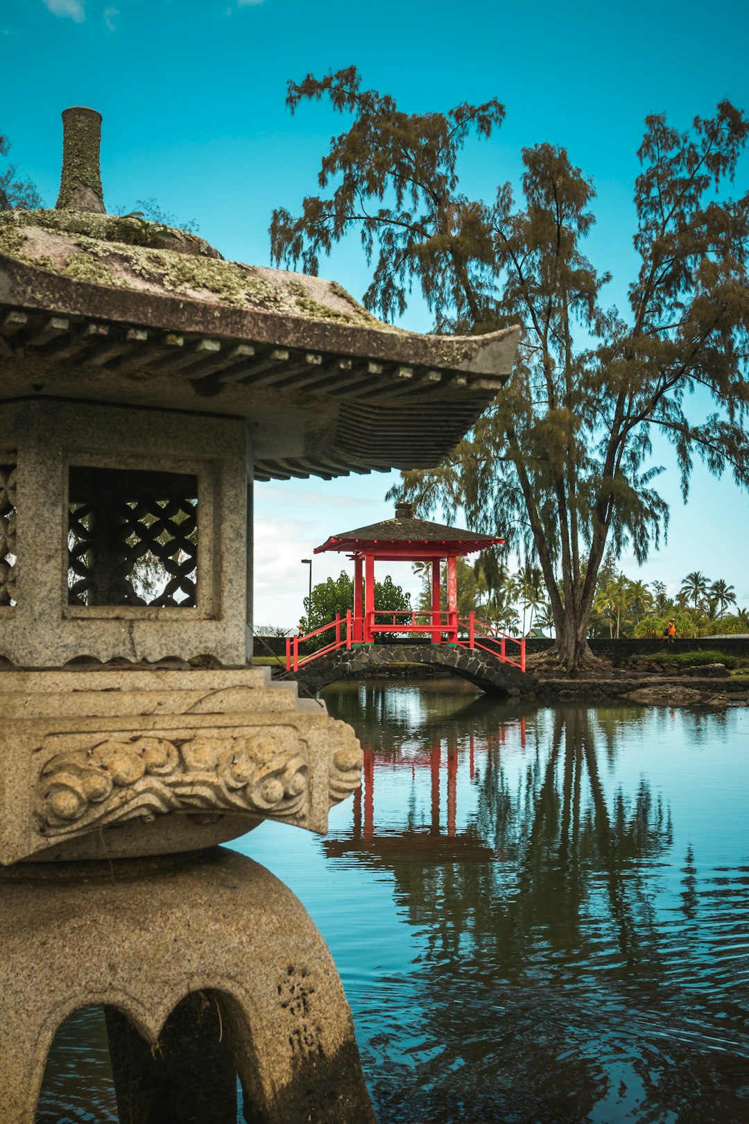 white concrete temple on body of water neat red bridge