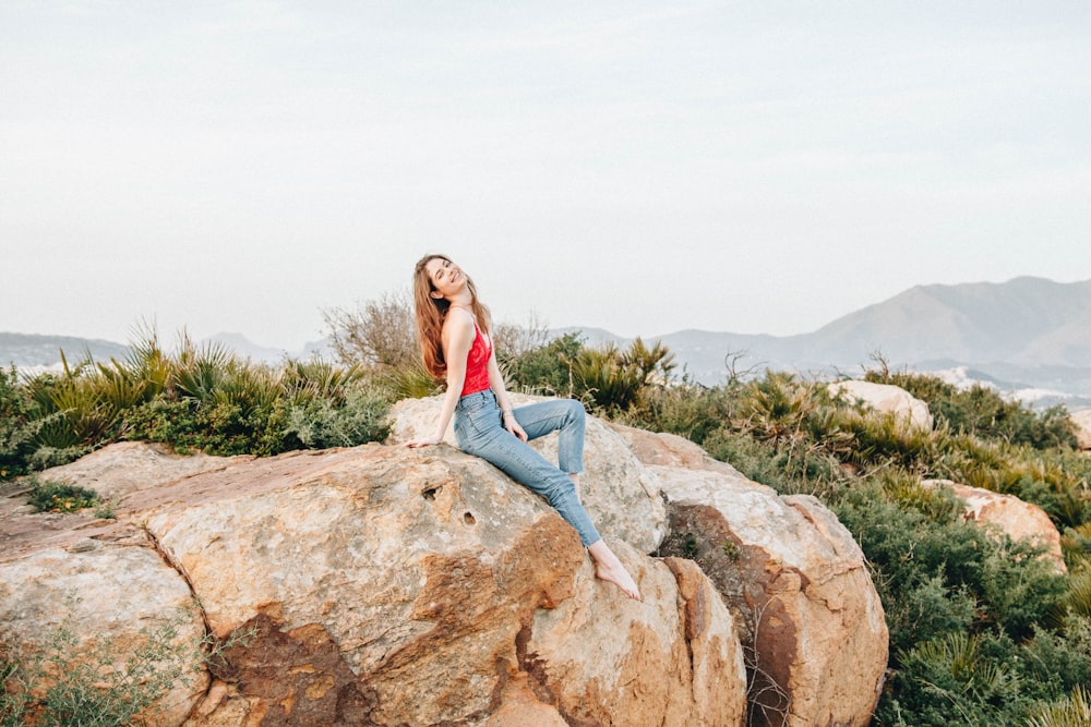 woman sitting on rock next to bushes