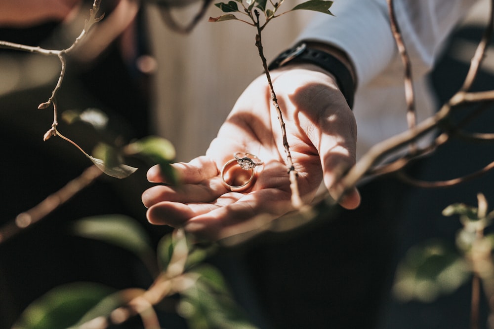 person holding gold-colored ring outdoor during daytime