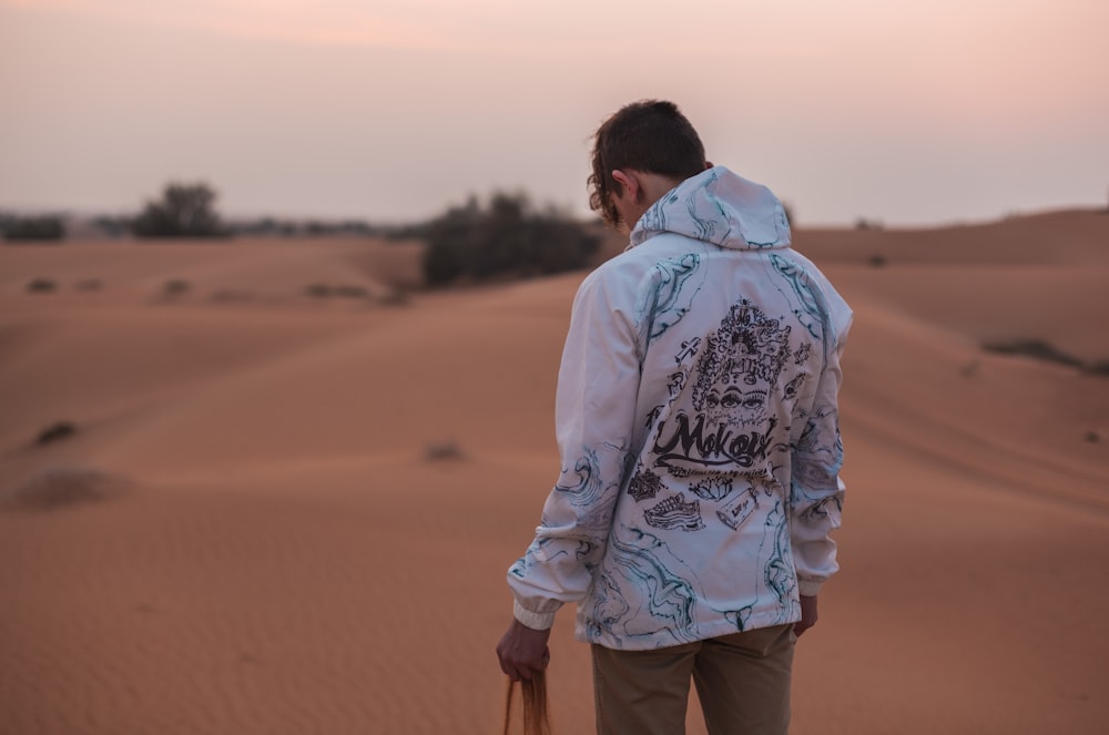 man standing on desert holding sand during daytime