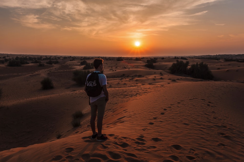 golden hour photography of man standing on top of a hill