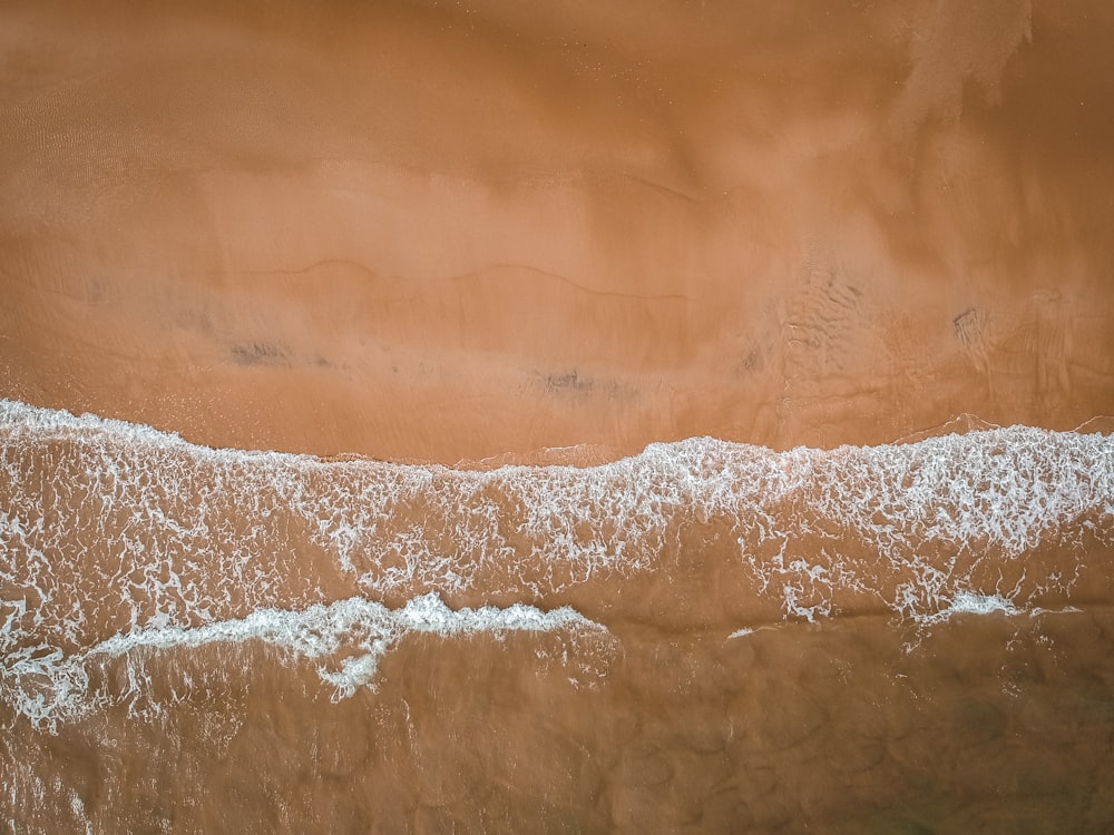 an aerial view of a sandy beach with waves