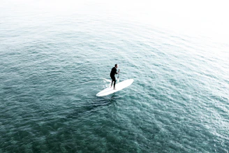 A vibrant photo of a paddleboarder gliding across calm turquoise waters under a sunny sky.