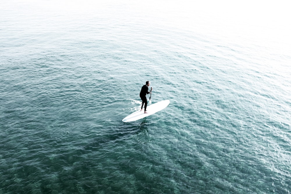 uomo che cavalca la tavola da surf sullo specchio d'acqua