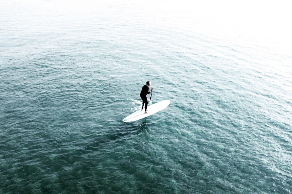 man riding surfboard on body of water