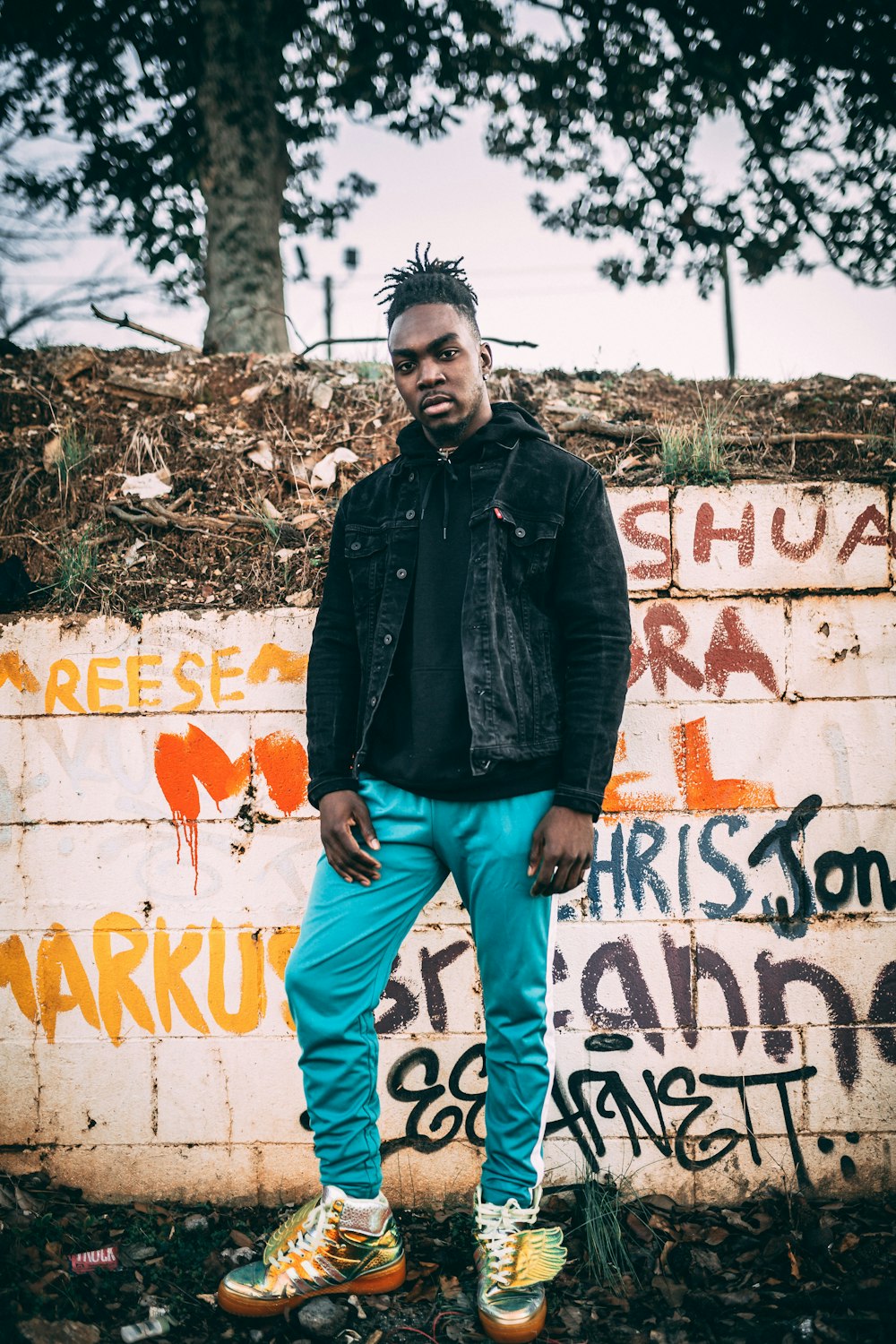 a man standing in front of a graffiti covered wall