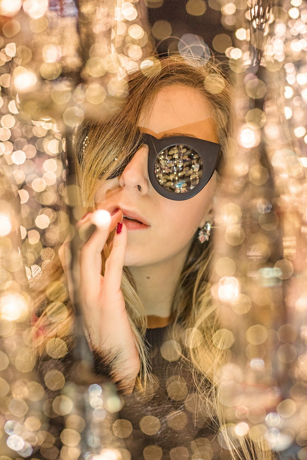 woman holding lips with black framed sunglasses