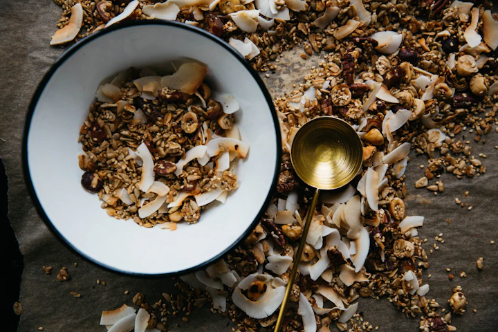 Muesli with coconut and nuts in a bowl beside a brass ladle
