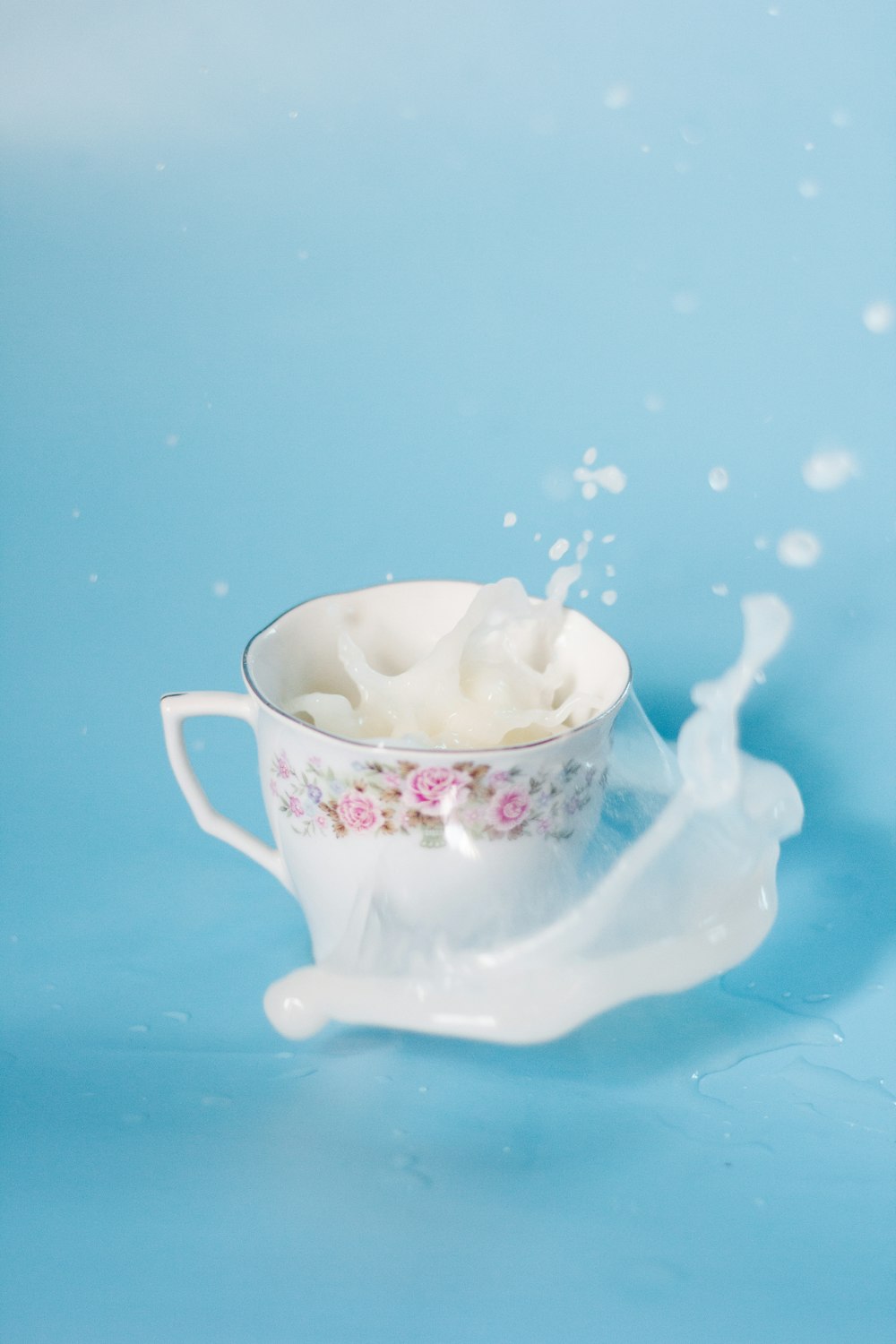 엎질러진 우유가 담긴 흰색과 분홍색 꽃무늬 세라믹 컵