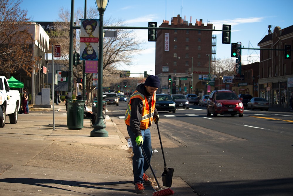 Mann reinigt die Straße in der Nähe der Ampel
