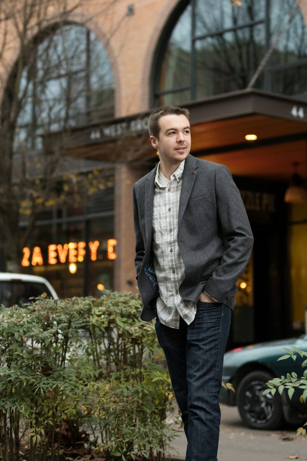 man wearing jacket near green vehicle beside building at daytime