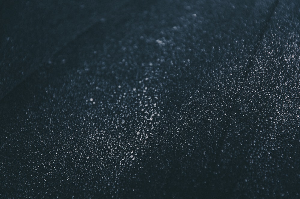a close up of a black surface with drops of water