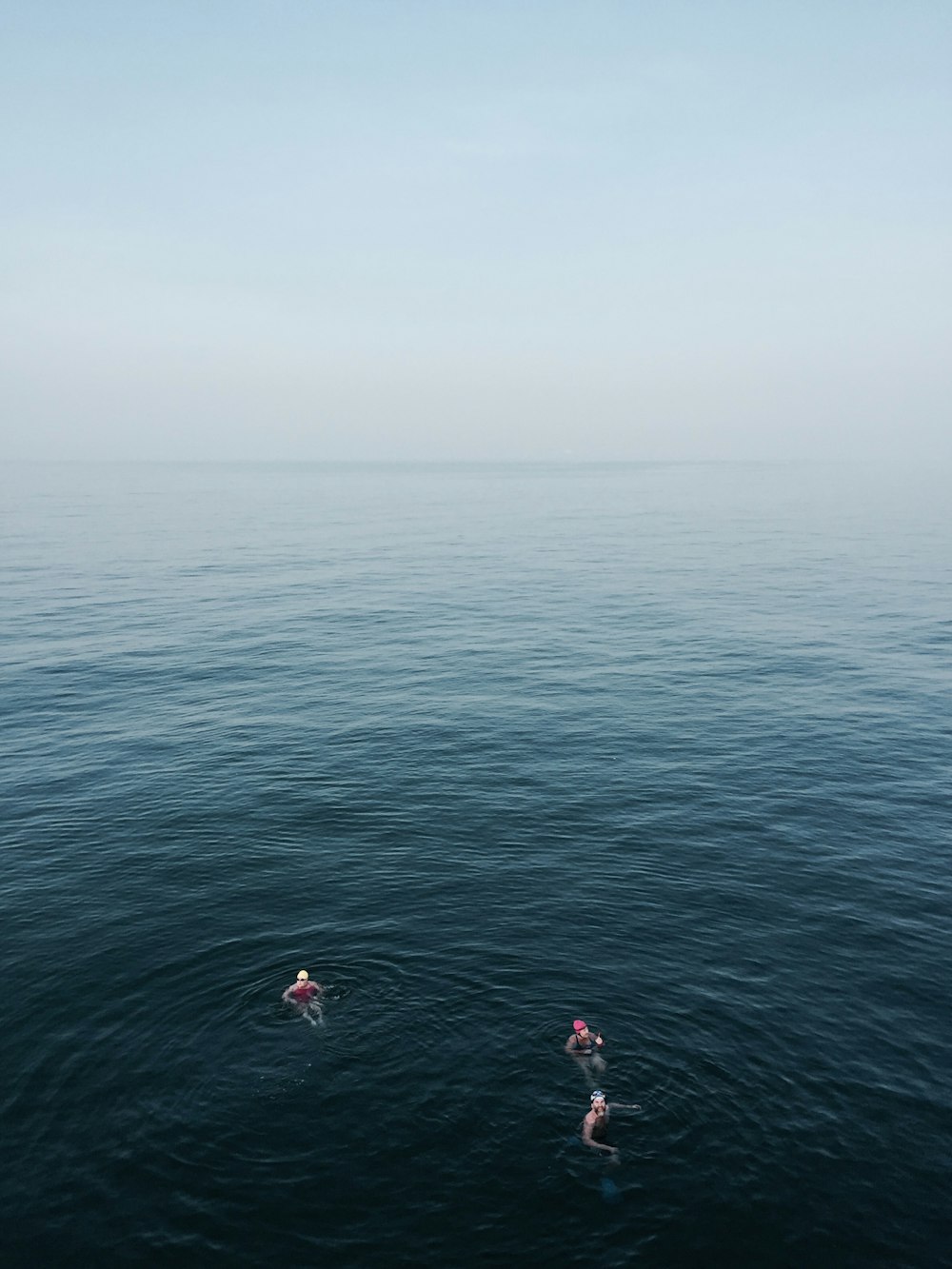 three people floating on body of water