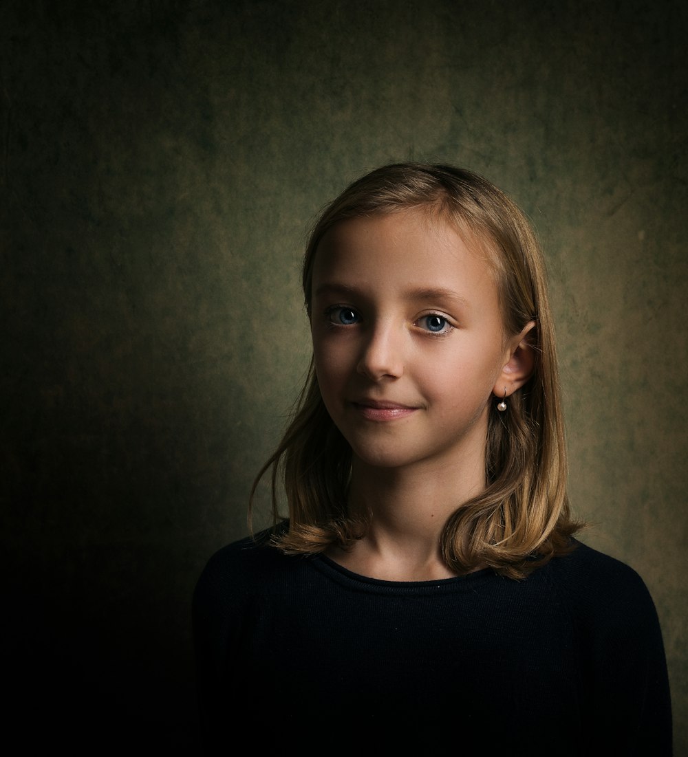 Foto de la niña de pie cerca de la pared gris