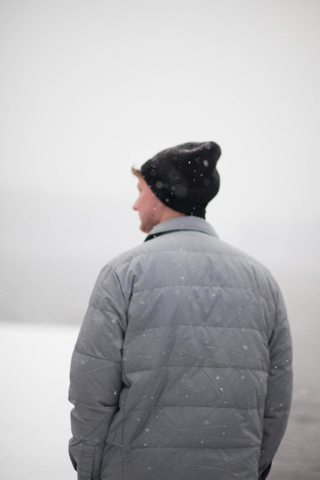 man wearing gray jacket under snow