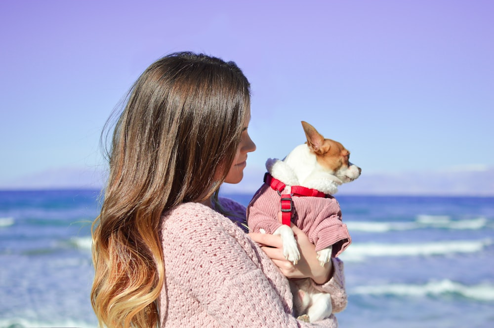 woman holding white dog on seashore