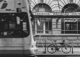 grayscale photography of bicycle parked at steel fence