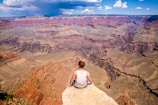 person sitting on cliff during daytime