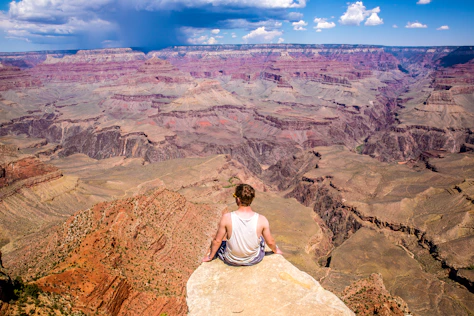 person sitting on cliff during daytime