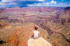 person sitting on cliff during daytime
