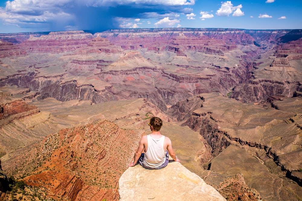 person sitting on cliff during daytime