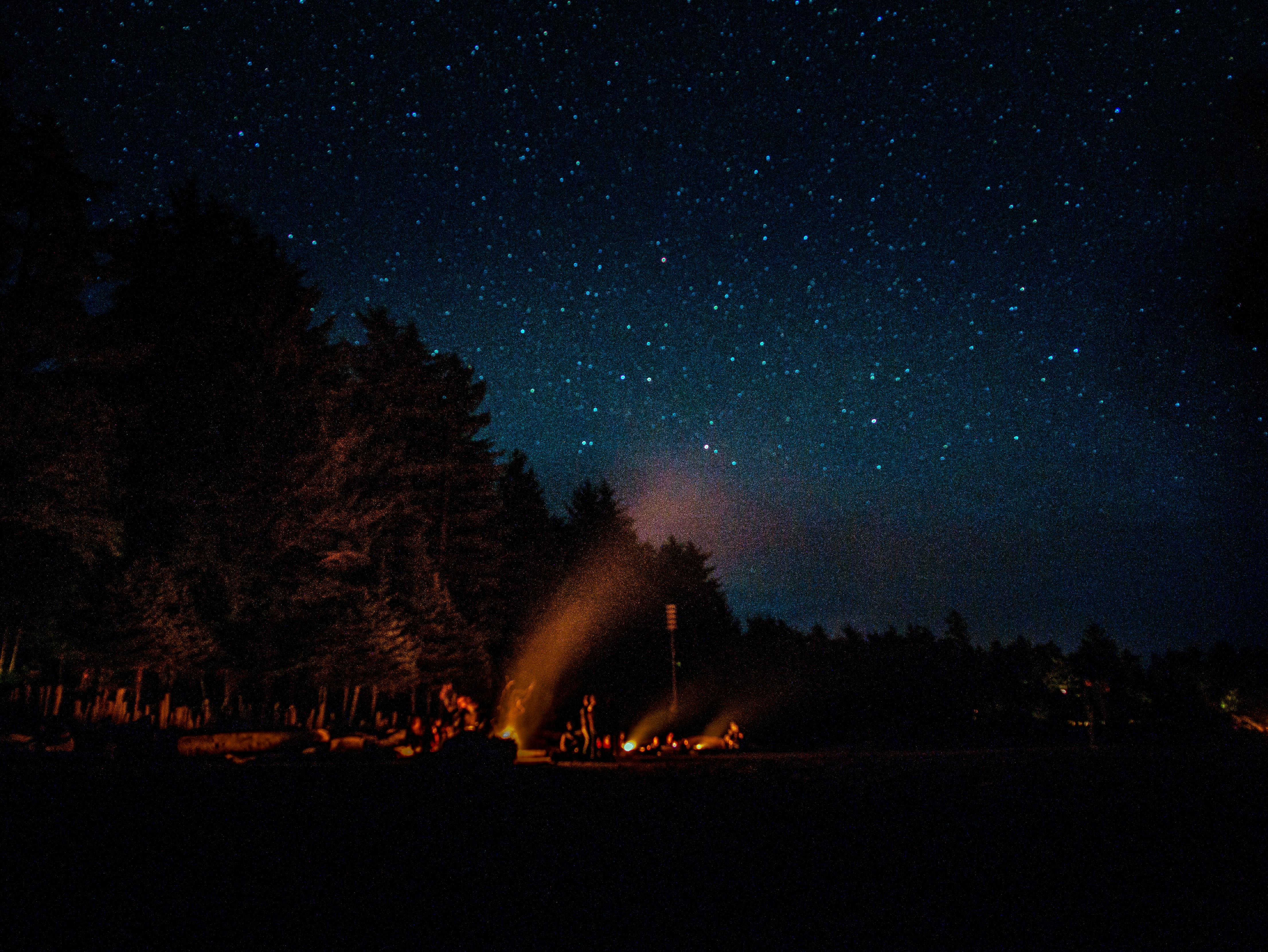people having bonfire under blue sky filled with stars at night time