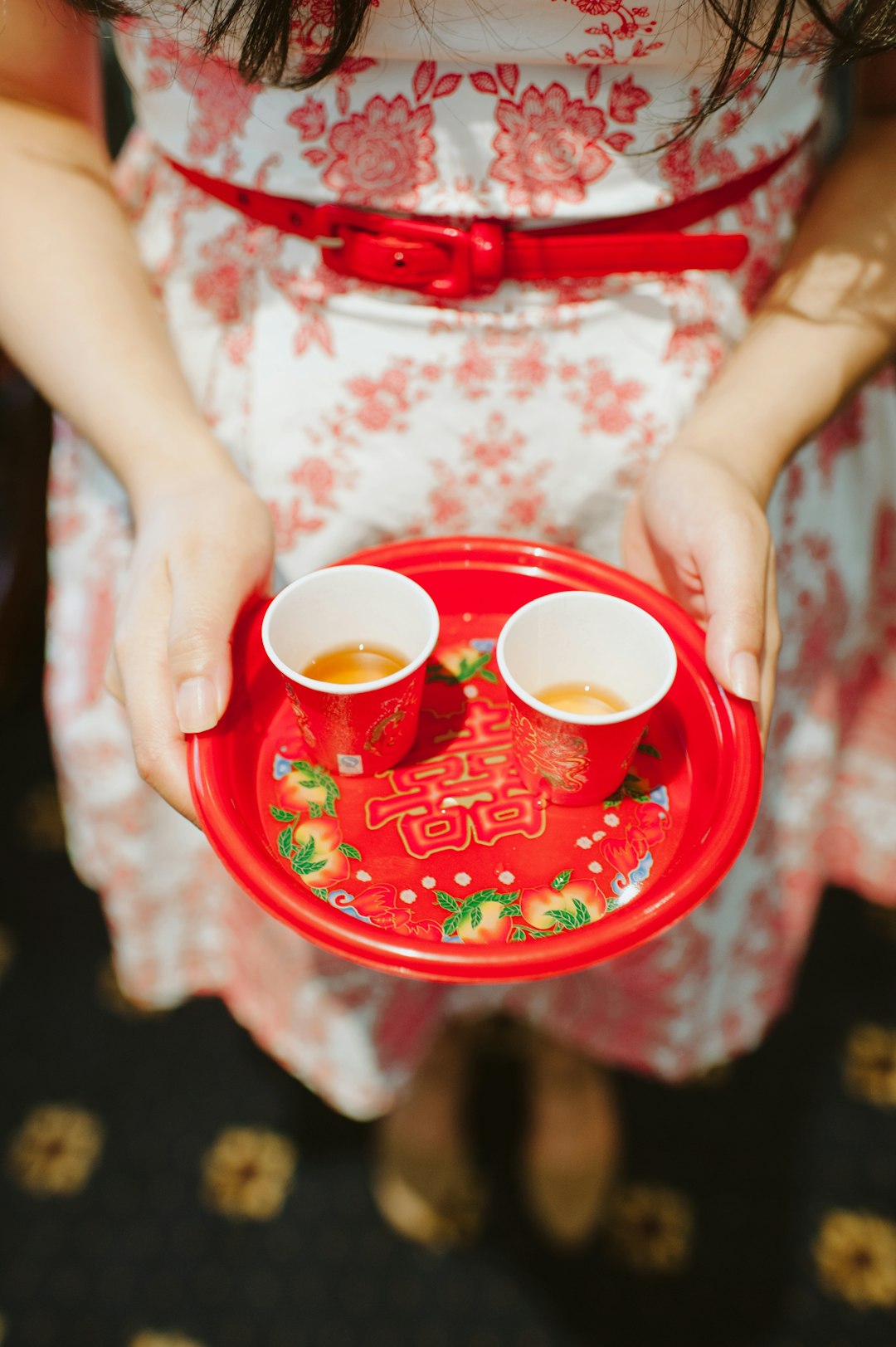 person holding plastic plate with two red cups