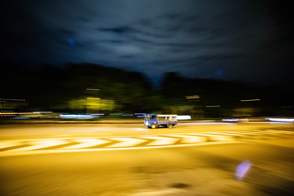 blue truck passing through asphalt road during nighttime