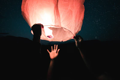 Close-up of hands holding a glowing constellation map under a twilight sky.