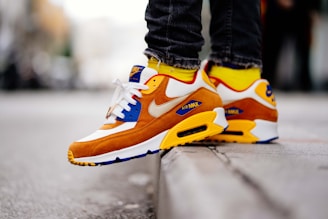 close-up photography of person wears brown-and-white Nike Air Max