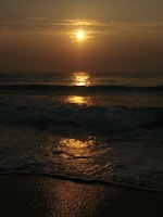 A serene sunset over a calm beach, reflecting warm golden hues.