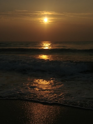 A serene sunset over a calm beach, reflecting warm golden hues.