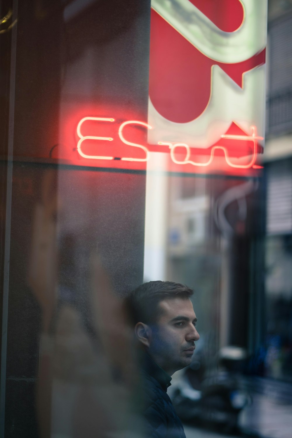 man wearing black jacket standing near signage and building at daytime