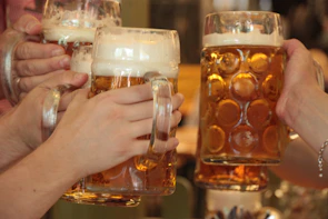 Close-up of frothy beer glasses clinking in a celebratory toast on the moving beer bike.