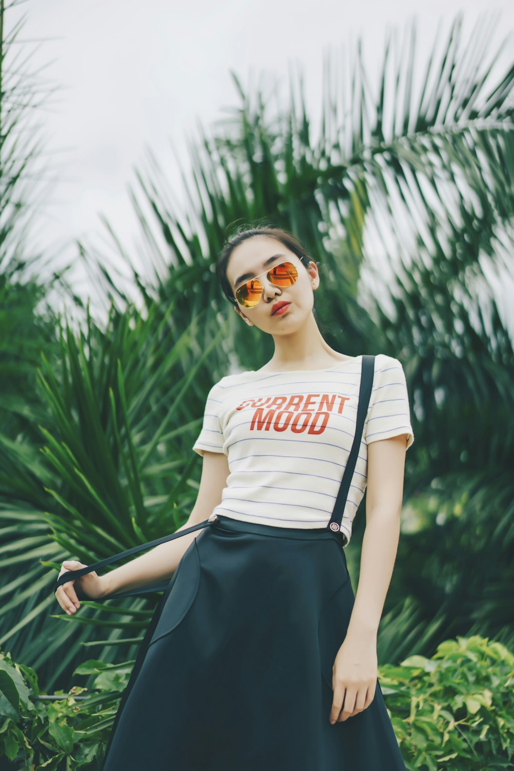 woman standing behind palm plants