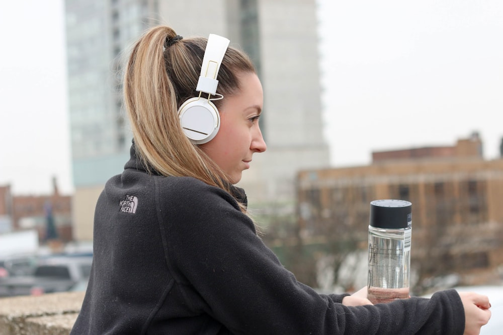 woman wearing black The North Face jacket and white headphones