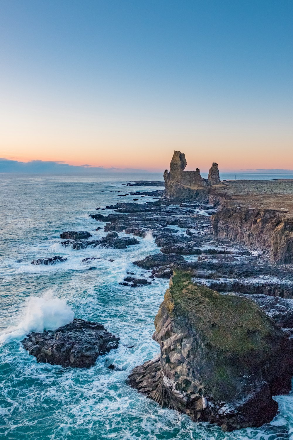 Fotografía de paisaje de olas rompiendo en rocas cerca de acantilado