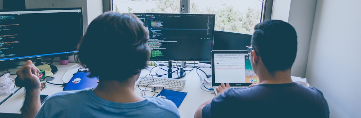 two men using computer and laptop