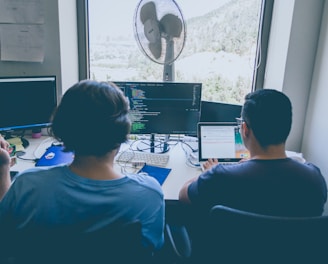 two men using computer and laptop