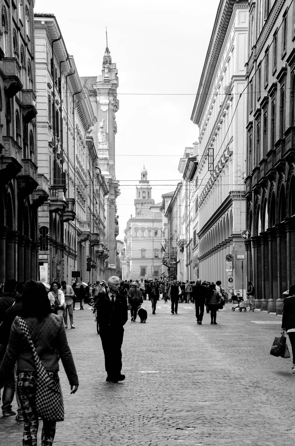 a group of people walking down a street next to tall buildings