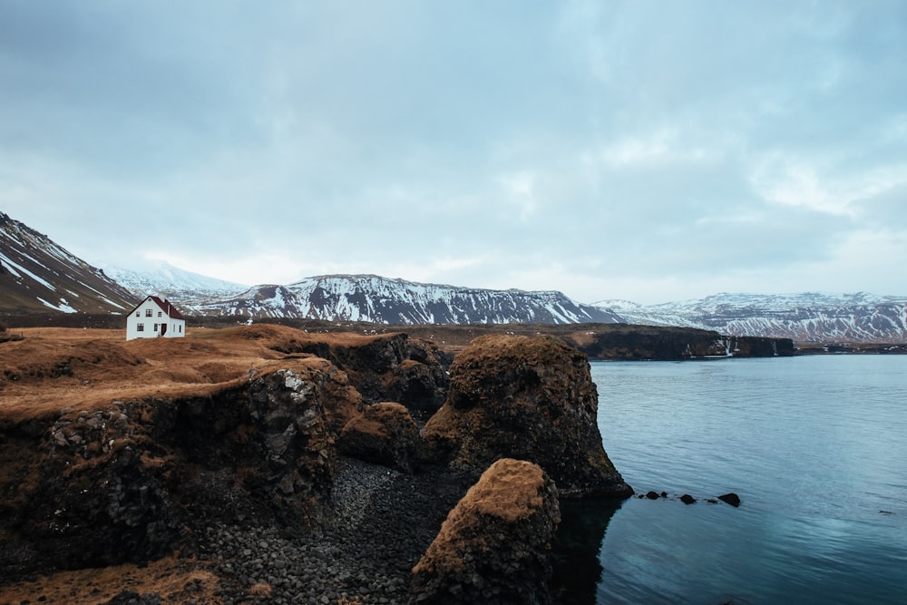 white and blue house on cliff near sea