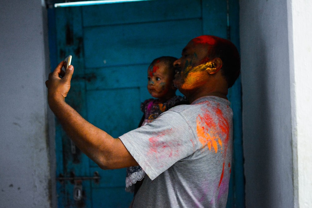 man carrying child while taking selfie